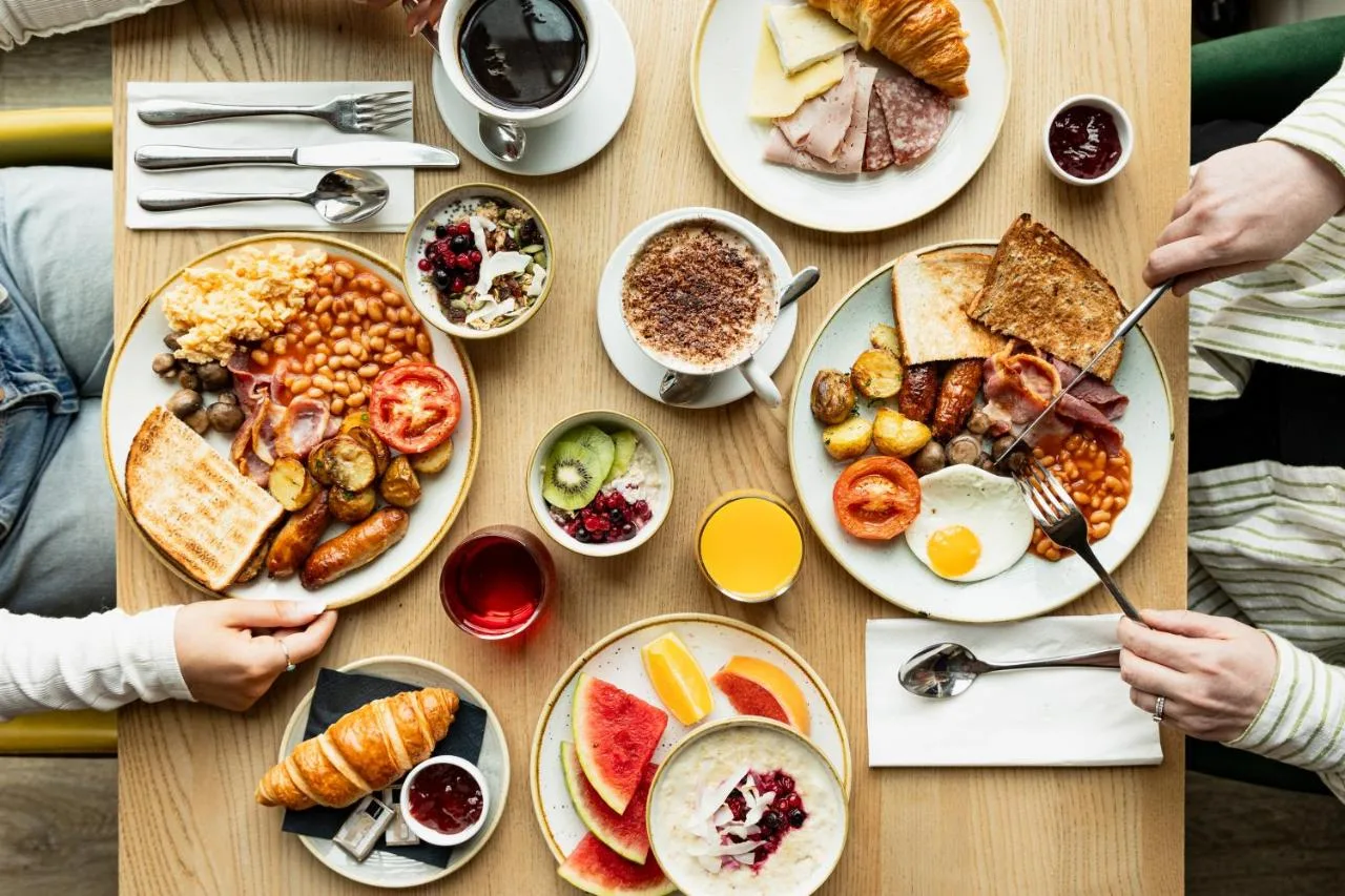 a table with plates of breakfast food on it at Leonardo Hotel Newcastle Quayside in Newcastle upon Tyne